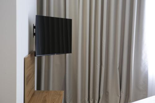 a flat screen tv on a wall next to a curtain at Hotel La Rosa in Tirane