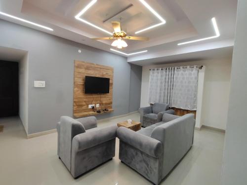a living room with two chairs and a flat screen tv at Nandan Suits in Mysore