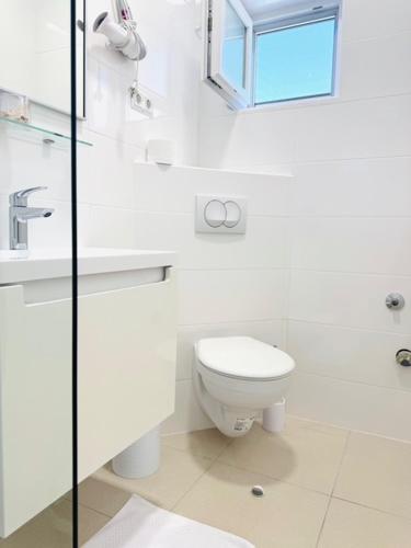 a white bathroom with a toilet and a sink at Apartman Sanja in Vlašići