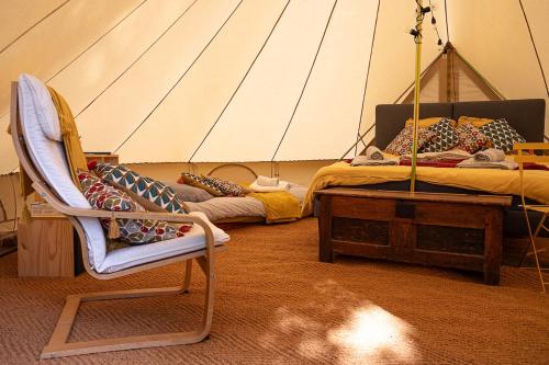 - une chambre avec un lit et une chaise dans une tente dans l'établissement Nuit *é* Toilée à la Ferme du Petit Puyaume, à Montravers