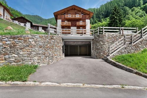 a building with a stone wall and a garage at La Casa di Larice in Val di Sole in Rabbi