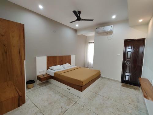 a bedroom with a bed and a ceiling fan at Nandan Suits in Mysore