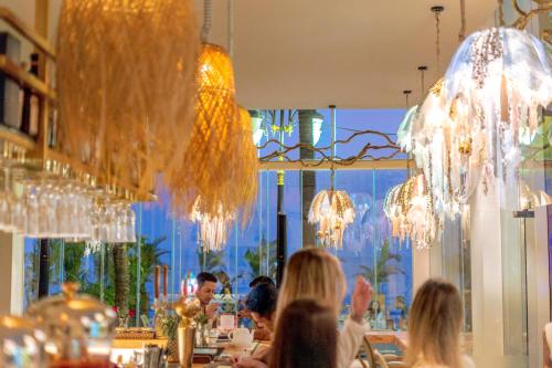 a group of people sitting at a restaurant with chandeliers at Queenco Hotel & Casino in Sihanoukville