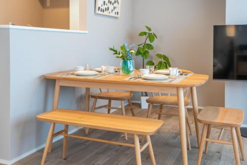 a wooden table with four chairs and a tv at Starry Stay Suite Improve Nishimagome in Tokyo