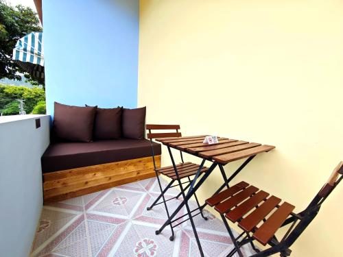 a balcony with a table and chairs and a couch at Cloud Tree Inn Boutique Guesthouse XiChong DaPeng ShenZhen 深圳大鹏西涌云树里民宿Yun Shu Li in Shenzhen