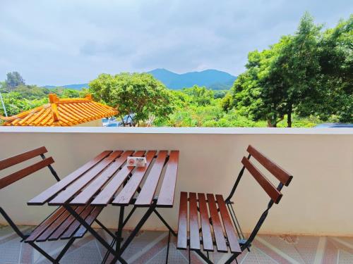 a wooden table and two chairs on a balcony at Cloud Tree Inn Boutique Guesthouse XiChong DaPeng ShenZhen 深圳大鹏西涌云树里民宿Yun Shu Li in Shenzhen