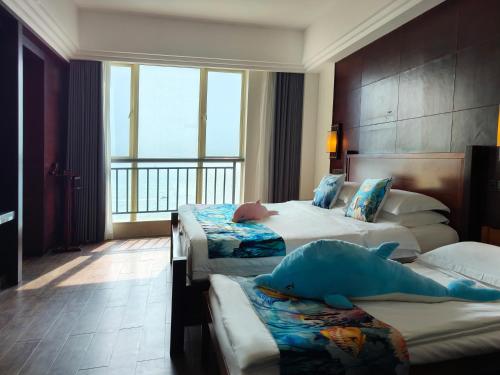 a hotel room with two beds and a large window at Shengyi Holiday Villa Hotel in Sanya