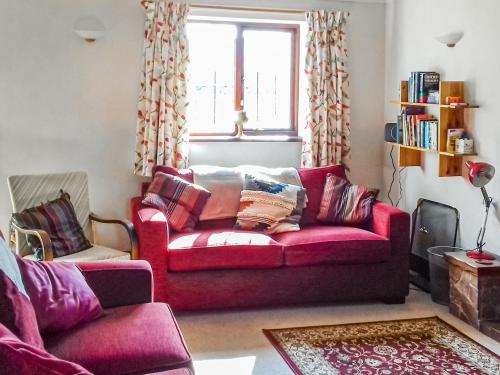 a living room with a red couch and a window at Kay's Cottage in Buckfastleigh