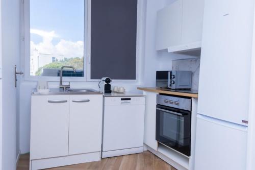une cuisine blanche avec des appareils électroménagers blancs et une fenêtre dans l'établissement Spacieux appartement 3 pièces 3 SDE, proche mer, à Nice