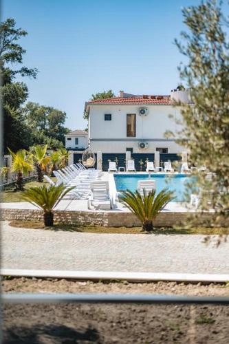 a pool with white chairs and a house at M&N Holiday Resort in Ulcinj