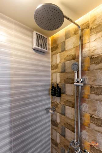 a shower in a bathroom with a wooden wall at Desert Rose Village in Al Khatim