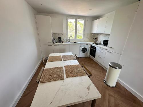 une cuisine avec des armoires blanches et une table à l'intérieur dans l'établissement Appartement lumineux, spacieux et idéalement situé, à Saint-Raphaël