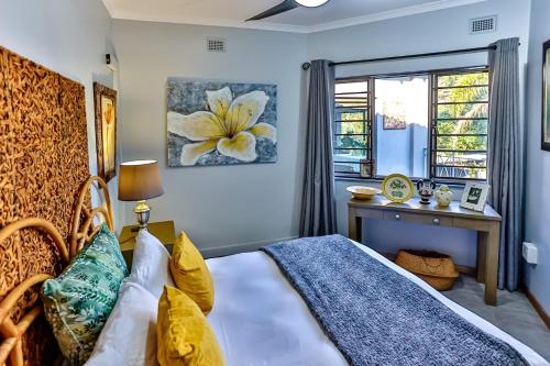a bedroom with a bed and a desk and a window at RR001 Robbins Road - A home away from home in Ballito