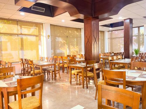 a dining room with wooden tables and chairs at Aqaba Gulf Hotel By FHM in Aqaba