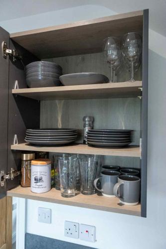 a shelf with plates and wine glasses and dishes at Eider Lodge in Helsey
