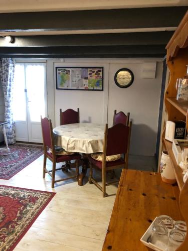 une salle à manger avec une table, des chaises et une horloge dans l'établissement La Maison de Lavande, à Queaux