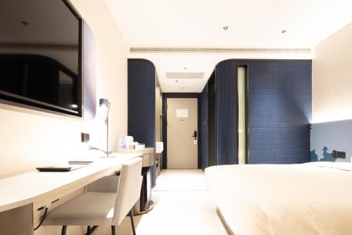 a bedroom with a bed and a desk with chairs at Atour Light Hotel Hangzhou West Lake Lakeside Pedestrian Street in Hangzhou