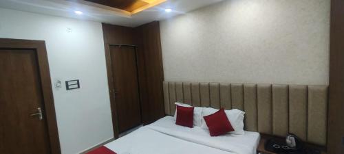 a bedroom with a bed with two red pillows at Hotel New Arcadia in Bhopal