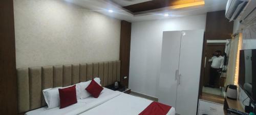 a bedroom with a bed with red pillows and a mirror at Hotel New Arcadia in Bhopal