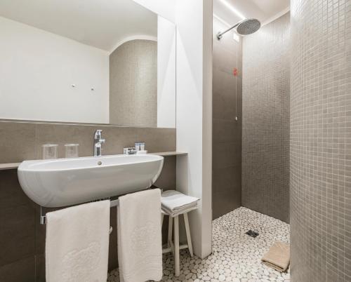 a bathroom with a sink and a shower with towels at Hotel Metropole Suisse in Como