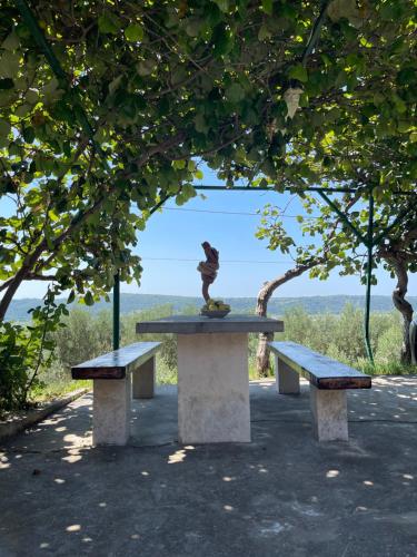a statue sitting on top of a picnic table with two benches at 4 Roses Residence in Sečovlje
