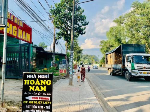a man and a child walking down a street with a truck at Hoàng Nam Motel Bình Dương in Hoi Nghia