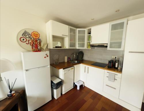  La cuisine est équipée de placards blancs et d'un réfrigérateur. dans l'établissement Appartement avec balcon, à Paris