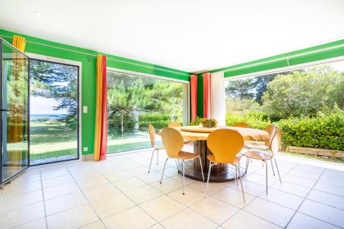 a dining room with a table and chairs and sliding glass doors at Coin de paradis face à l'océan in Loctudy