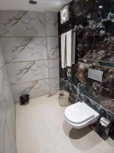 a bathroom with a toilet and a marble wall at Hotel New Arcadia in Bhopal