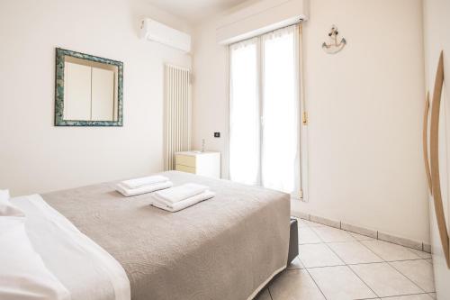 a white bedroom with a bed with towels on it at Marty Sweet Home, Cattolica Centro in Cattolica