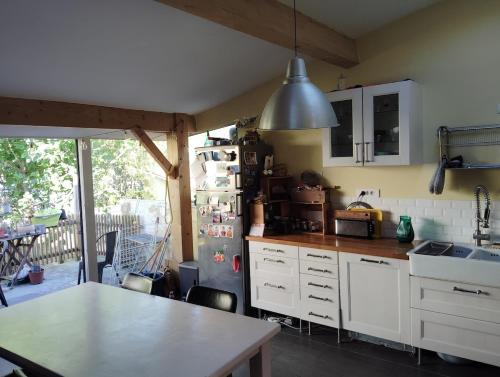 une cuisine avec des armoires blanches et une table à l'intérieur dans l'établissement Pretty house, à Bordeaux