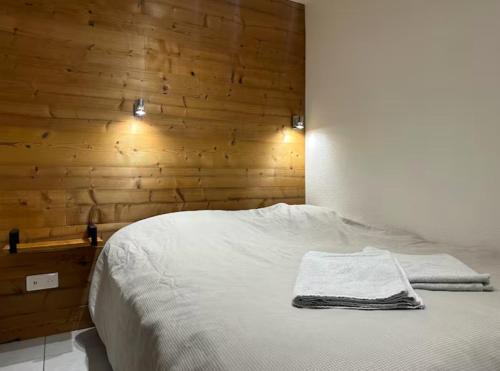 - une chambre avec un lit blanc et un mur en bois dans l'établissement Le Repaire Sarrecrochet, au Puy-en-Velay