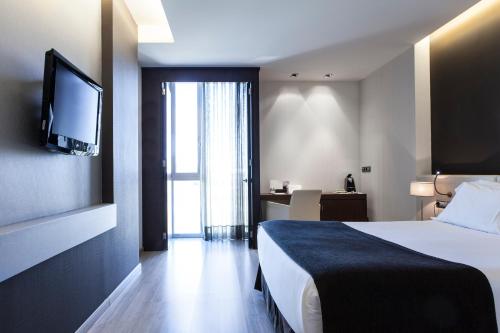 a hotel room with a bed and a flat screen tv at Hotel Diagonal Plaza in Zaragoza