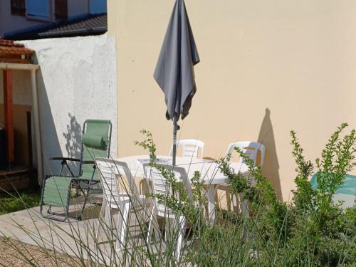 a table with chairs and an umbrella in a yard at L'étoile du matin in Terville