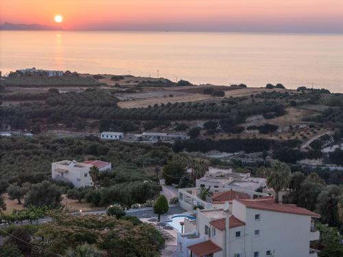 an aerial view of a village with the sun setting over the ocean at Lofos Panorama Apartments in Prínos