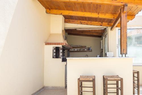 a kitchen with two bar stools and a wooden roof at Lofos Panorama Apartments in Prínos