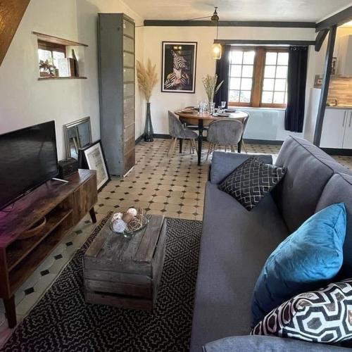 a living room with a couch and a table at La Chaumière aux Animaux in Touffreville-la-Corbeline