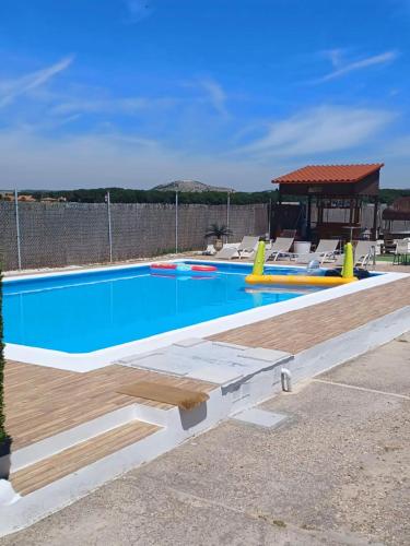 a pool with a wooden deck and a gazebo at Villa La Espiga in Valladolid