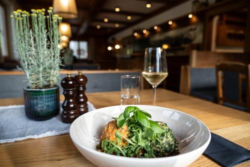 a white bowl of food on a table with a glass of wine at Gasthof Schöntal in Werfenweng