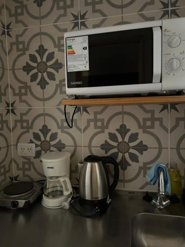 a microwave sitting on a shelf above a kitchen counter at Maipu Apartment Studio in Buenos Aires