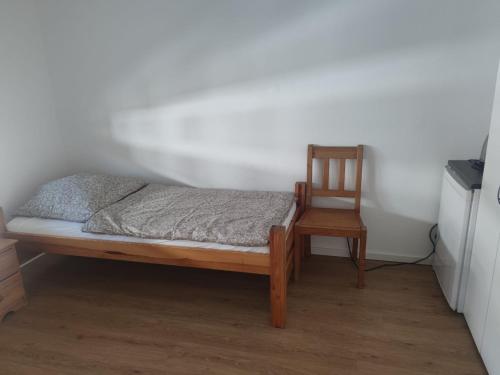 a bed and a wooden chair in a room at Monteurzimmer Mühlheim am Main Nähe S-Bahn in Mühlheim