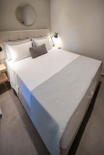 a large white bed in a room with a mirror at Zerynthos Apartments in Therma