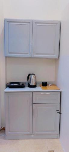 a kitchen with white cabinets and a tea kettle on a counter at نسمة كيان للشقق المخدومة in Jeddah