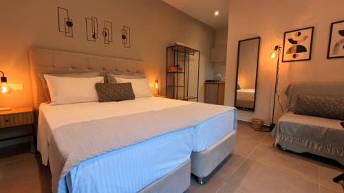 a bedroom with a large white bed and a mirror at Zerynthos Apartments in Therma
