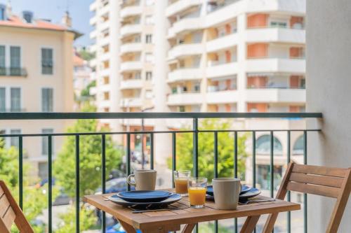 une table en bois avec deux verres de jus d'orange sur un balcon dans l'établissement Appartement 3P - Cœur de Nice, Proche Plage, à Nice
