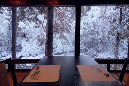 a table in front of a window with snow covered trees at Wanosato in Takayama