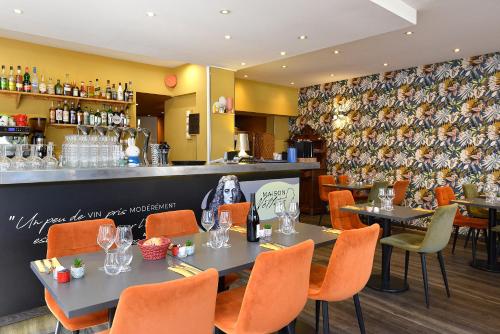 a restaurant with tables and chairs and a bar at Logis Hôtel Restaurant Maison Voltaire in Amboise