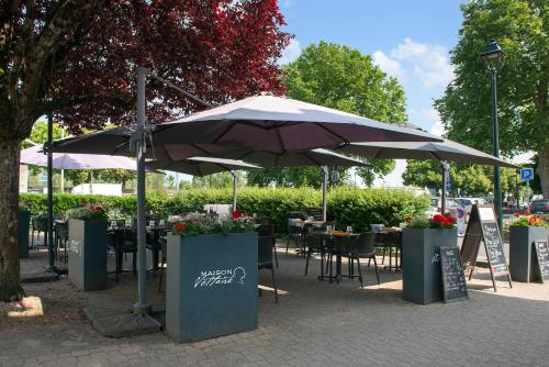 an umbrella on a sidewalk with tables and chairs at Logis Hôtel Restaurant Maison Voltaire in Amboise