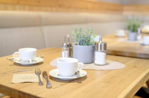 een houten tafel met twee koffiekopjes en keukengerei bij Landhotel Augustin in Bad Staffelstein