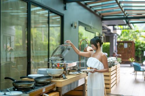 a woman standing in a kitchen preparing food at Wyndham Garden Naithon Phuket in Nai Thon Beach